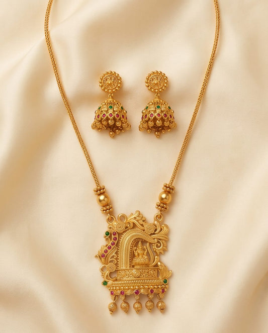 Gold necklace with intricate design and matching earrings on a beige fabric background