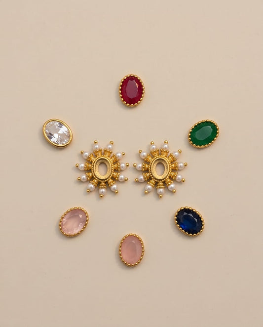 Collection of gold and gemstone earrings on a beige background