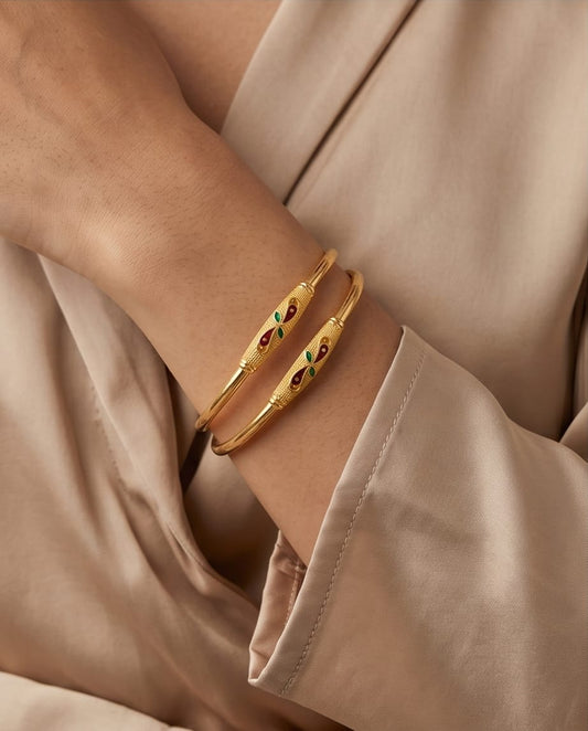 Gold bracelet with embedded stones on a beige background