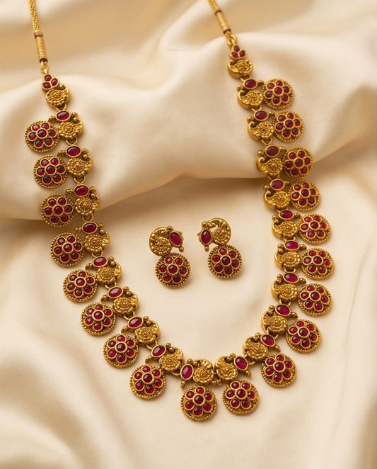Gold necklace with red gemstones on a beige fabric background